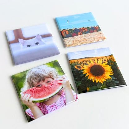 Image shows a flat lay of a set of four square photo magnets with a variety of images on them.